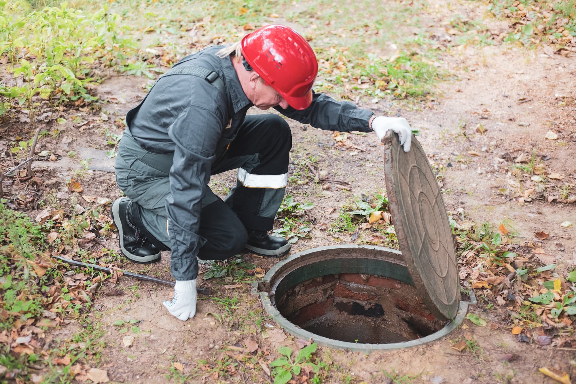 un fontanero con casco inspeccionando un sistema séptico